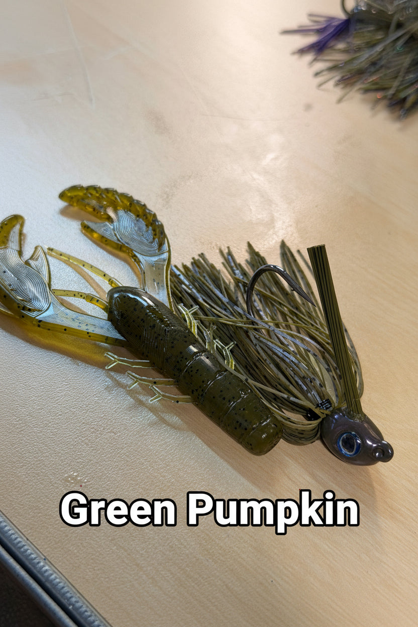 Soft plastic fishing lure with a green pumpkin segmented body, clear wings, and a skirt with metallic silver and olive-green strands, photographed on a light wood surface.